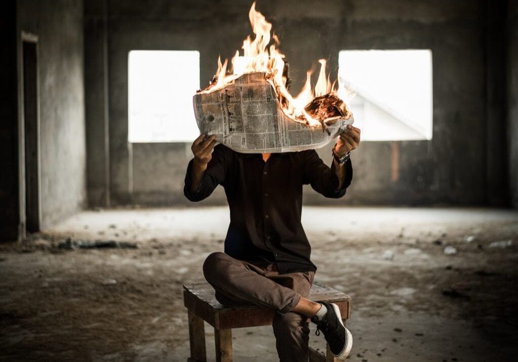 man holding newspaper on fire